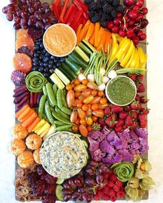 an array of fruits and vegetables with dips