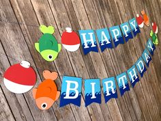 a happy birthday banner hanging on a wooden wall with fish and other items attached to it