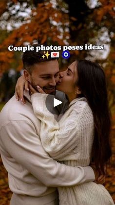 a man and woman embracing each other in front of trees with leaves on the ground