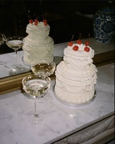 there are two cakes on the counter next to wine glasses