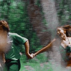 two people running in the grass holding hands