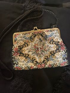 A vintage bag with an antique Victorian vibes look. This evening bag has a colorful needle point look (soft cloth fabric) in florals in front against a white background. It has a gold frame with a kiss clasp. Solid black in the back and it has a black cord like shoulder strap. *Rosary accent not included *Era: 1970's *Label: None *Fabric: Feels like cotton or a cotton blend *Condition: Gently used / No Flaws *Size: The bag measures 5 inches down and 8 inches across and it has a 19 inches strap Vintage Tapestry Pouch Bag, Vintage Embroidered Evening Bags, Vintage Evening Bag In Tapestry Material, Vintage Tapestry Bag For Formal Occasions, Vintage Tapestry Bag For Evening, Vintage Formal Tapestry Bag, Vintage Tapestry Multicolor Shoulder Bag, Antique Tapestry Evening Bag, Formal Vintage Tapestry Bag