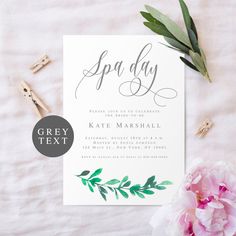 a white wedding card with greenery on it next to a pink carnation flower