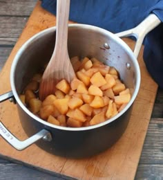 a wooden spoon in a pot filled with food on top of a wood cutting board