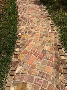 an old brick path with grass and trees in the background