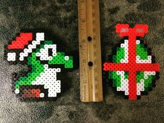 two pieces of perler bead art next to a measuring ruler on the floor