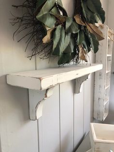 two wreaths are hanging on the wall next to a shelf with some plants in it