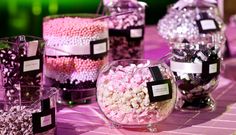 there are many different types of candies in glass bowls on the table with labels