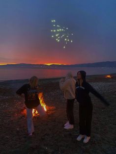 two girls are watching fireworks on the beach