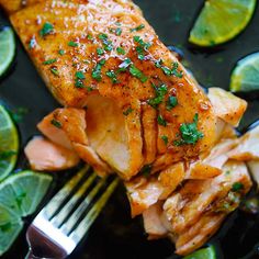 a piece of fish on a plate with lemons and lime slices