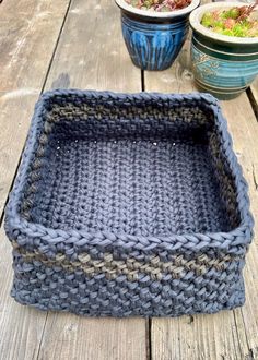 a gray basket sitting on top of a wooden table