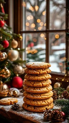 a stack of cookies sitting on top of a wooden table next to a christmas tree