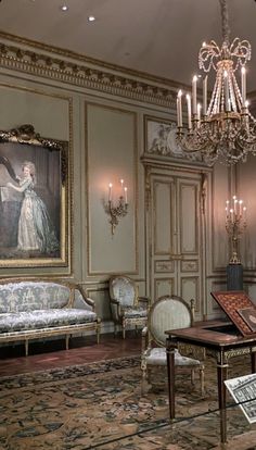 an ornately decorated living room with chandelier, couch and painting on the wall