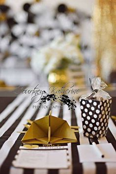 a black and white striped table cloth with polka dot napkins, gold origami boats