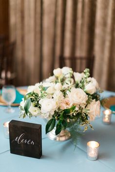 a vase filled with white flowers sitting on top of a blue table cloth covered table