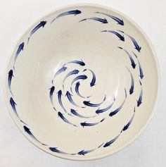 a blue and white bowl with black fish in it's spiral design on the bottom