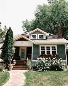 a gray house with white flowers in the front yard