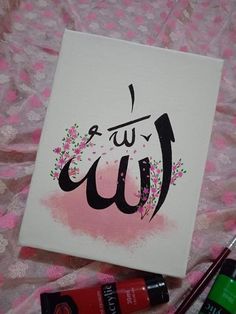 an arabic calligraphy is displayed on a pink and white background with some other items