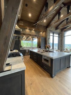 an open kitchen and living room with wood flooring, windows, and wooden beams