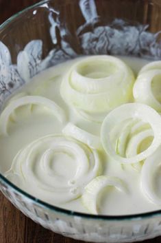 a glass bowl filled with cream on top of a wooden table