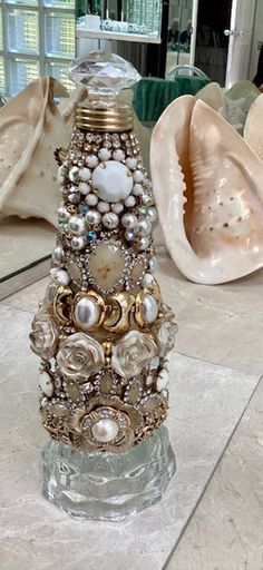 a decorative glass vase sitting on top of a marble floor next to seashells