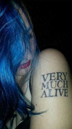 a woman with blue hair has a very much alive tattoo on her shoulder