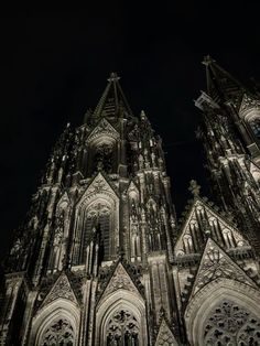 the cathedral is lit up at night with lights shining on it's towers and windows