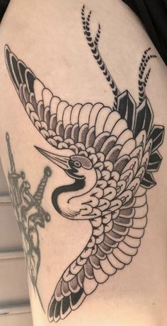 a bird tattoo on the back of a woman's thigh, with an arrow in it