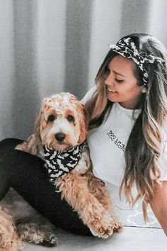 a woman sitting on the floor with her dog wearing a bandana and leggings