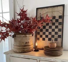 a potted plant sitting on top of a dresser next to plates and a candle