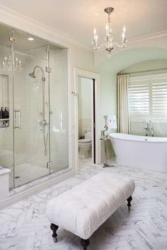 a white bathroom with a tub, shower and bench in it's center area