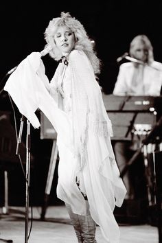 a woman standing on top of a stage next to a microphone