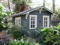 a small blue house surrounded by trees and plants