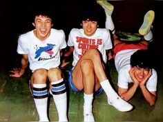 three young men sitting next to each other on the ground with their feet in the air