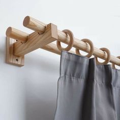 the curtain rod is attached to the wall by two wooden hooks, which are holding curtains