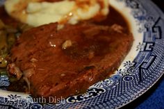 a blue and white plate topped with meat, mashed potatoes and gravy