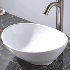 a white bowl shaped sink sitting on top of a counter next to a faucet