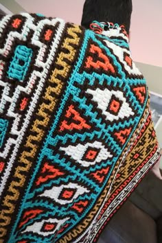 the back of a man's head covered by a colorful afghan style shawl