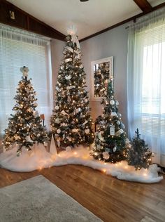 three decorated christmas trees in the corner of a room