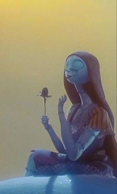 a woman sitting on top of a blue car holding a flower in her right hand