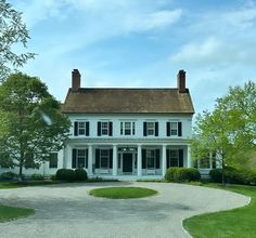 a large white house sitting on top of a lush green field