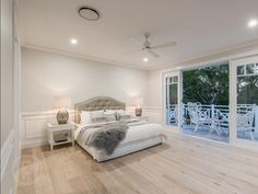 a large bedroom with white walls and wood flooring, along with sliding glass doors that lead to an outdoor deck