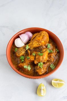 chicken curry in a bowl with garlic and cilantro on the side, ready to be eaten