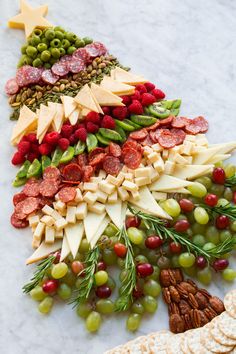 a christmas tree made out of cheese, crackers and grapes on a marble table