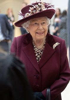 an older woman wearing a purple coat and hat