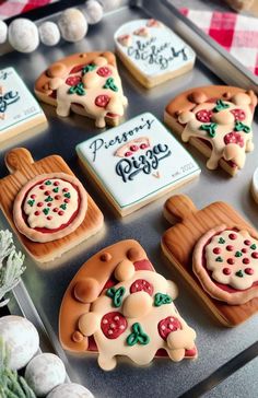 cookies decorated like pizzas are on a tray next to some candies and marshmallows