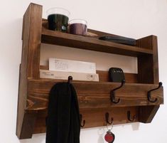 a wooden shelf with key hooks and other items hanging on it's sides,