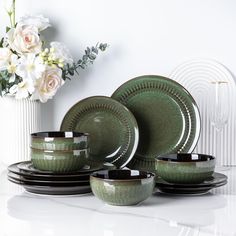 a set of green dinnerware with flowers in the background