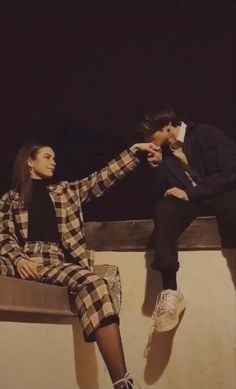 two people are sitting on a bench and one is touching the other's hand