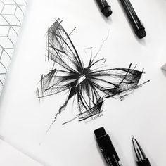 some pens are laying on top of a white paper with a butterfly drawn on it